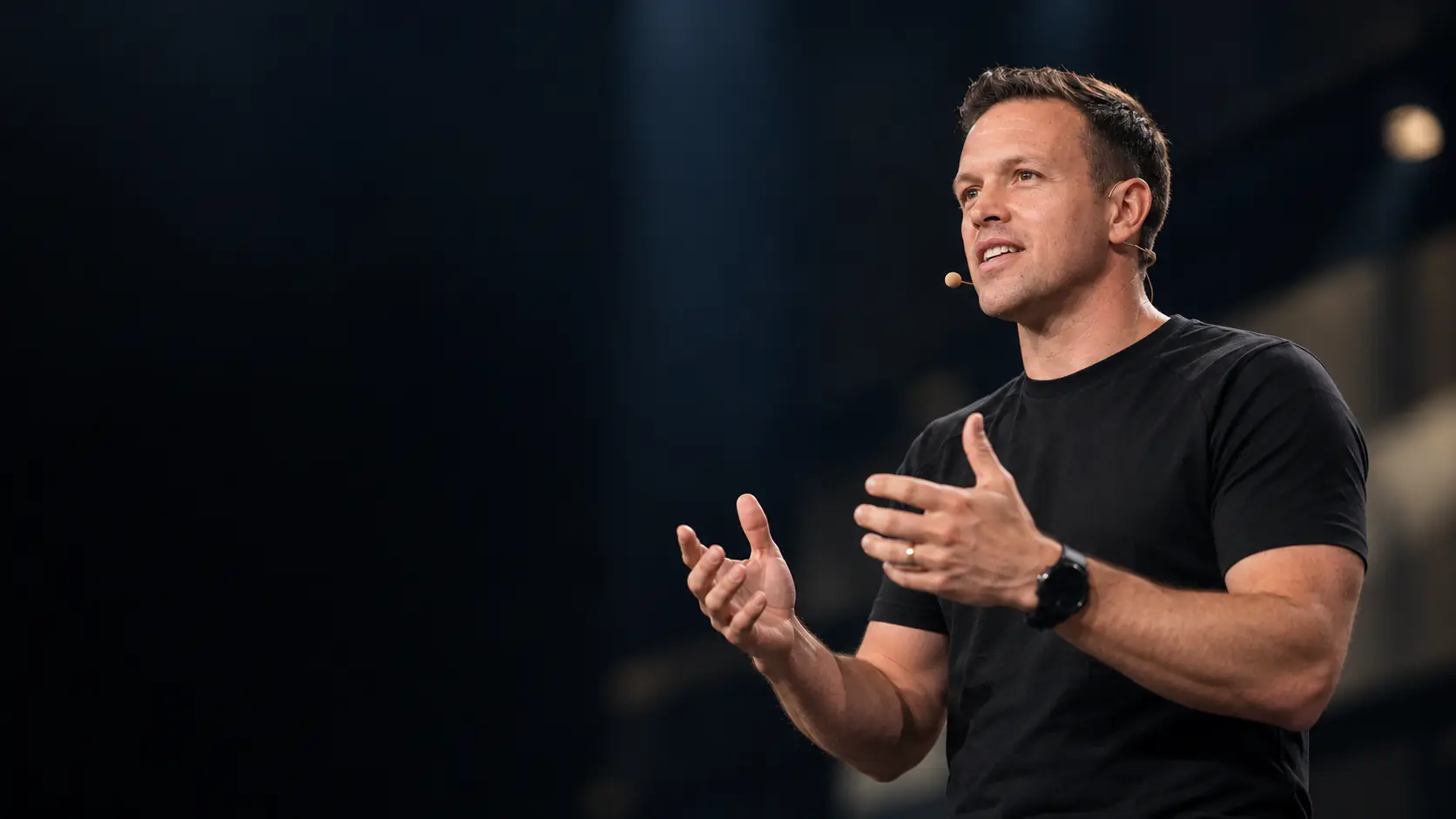 Ben Stocken speaking on stage to a large audience