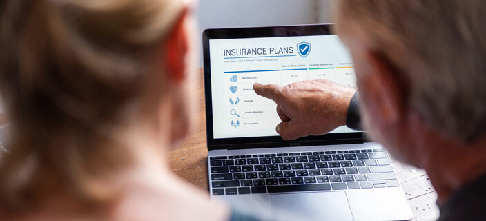 Two people reviewing insurance plans on a laptop