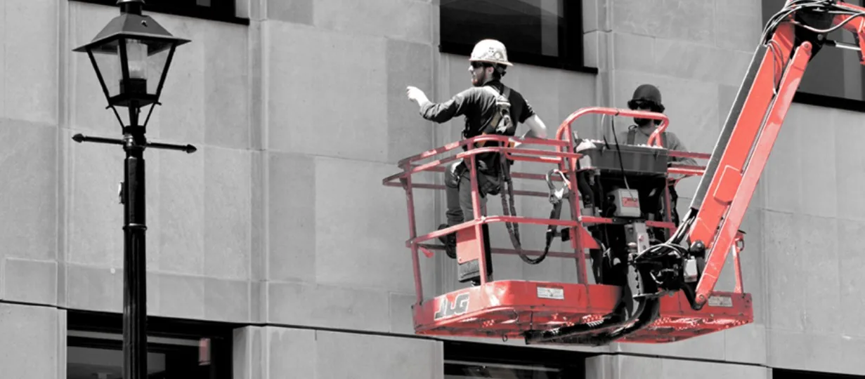 Two Potential Engineering QEWIs in a boom lift performing a hands-on FISP close-up facade inspection of a Manhattan limestone building