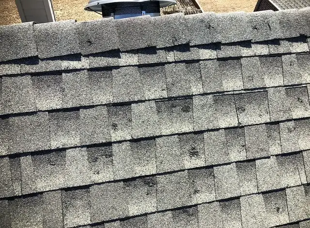 Multiple dark impact spots near a roof ridge