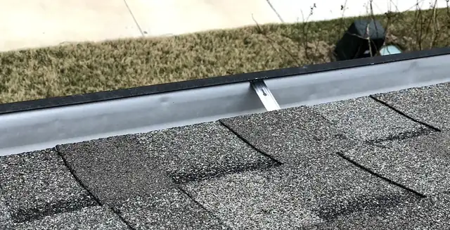 Gutter and hanger bracket along the shingle edge, checked during inspection
