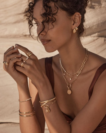 Woman wearing a gold pendant and stacked rings