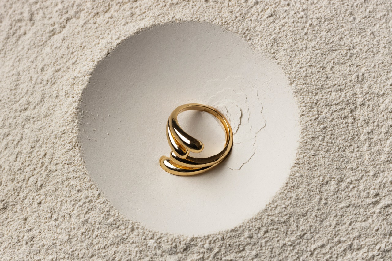 Sculpted gold wrap ring resting in a plaster dish