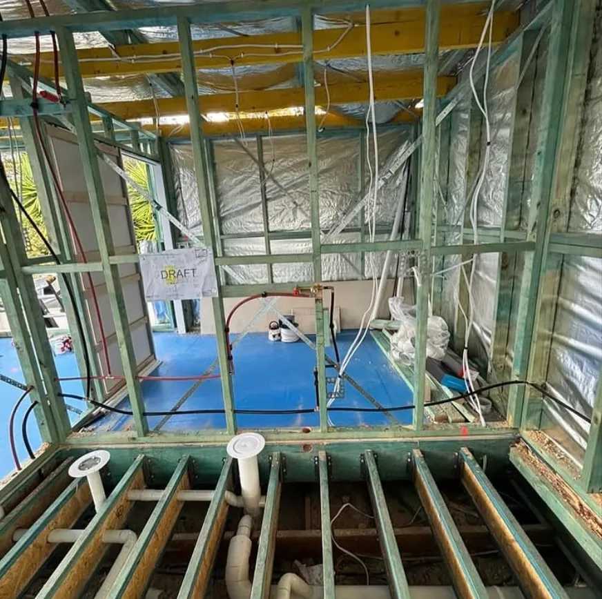 Wall framing with new plumbing rough-in and floor waste pipes in place