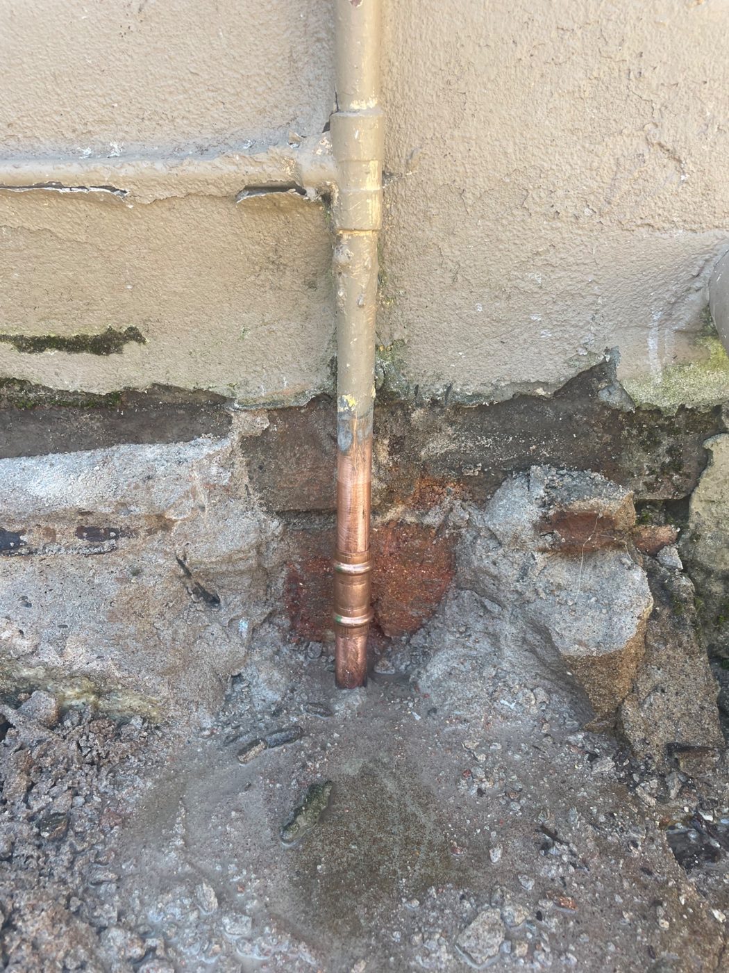 New copper water pipe section fitted at the base of an external wall in Cringila