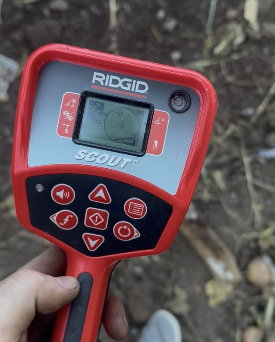 Handheld pipe locator being used to trace an underground pipe