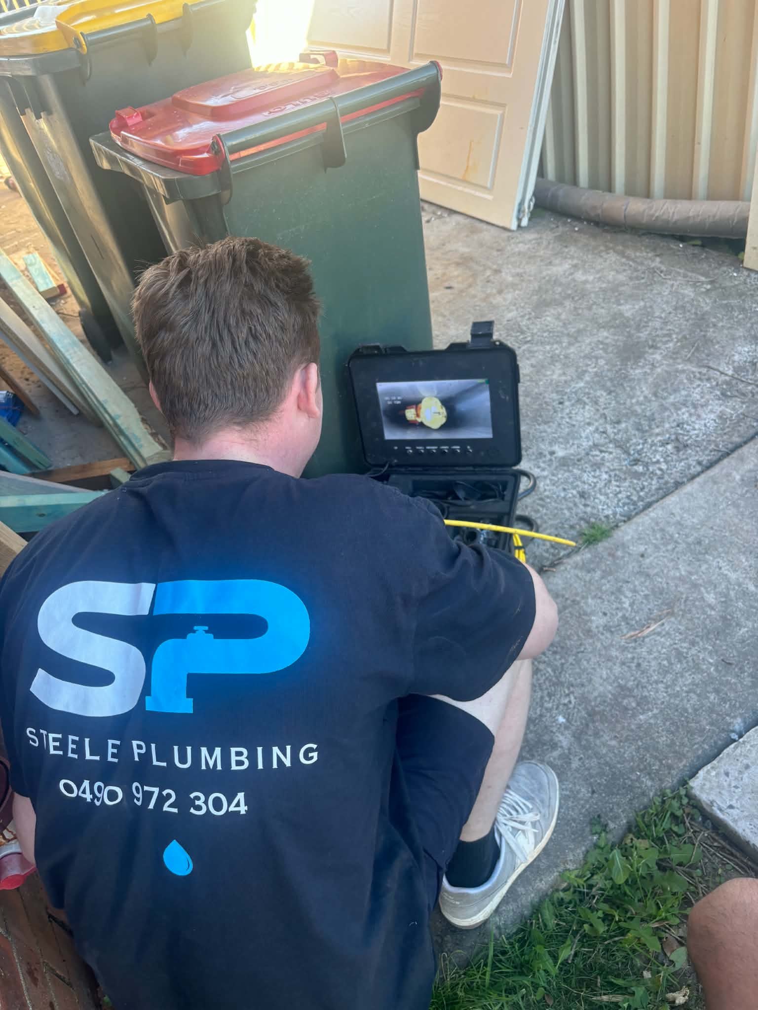 Steele Plumbing plumber running a drain camera inspection and checking the pipe on the monitor