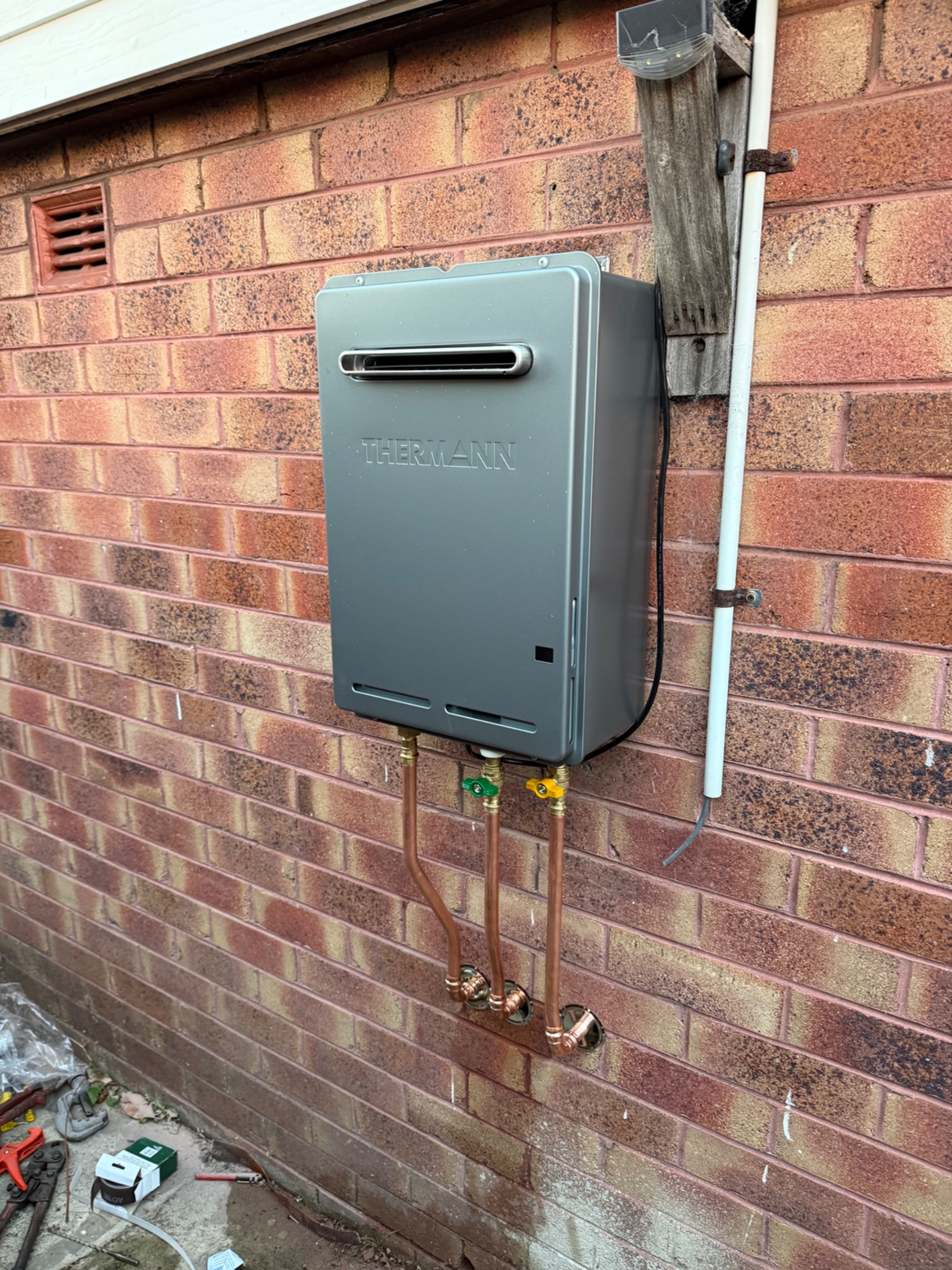New Thermann continuous flow hot water system with copper pipework and isolation valves on a brick wall in Woonona