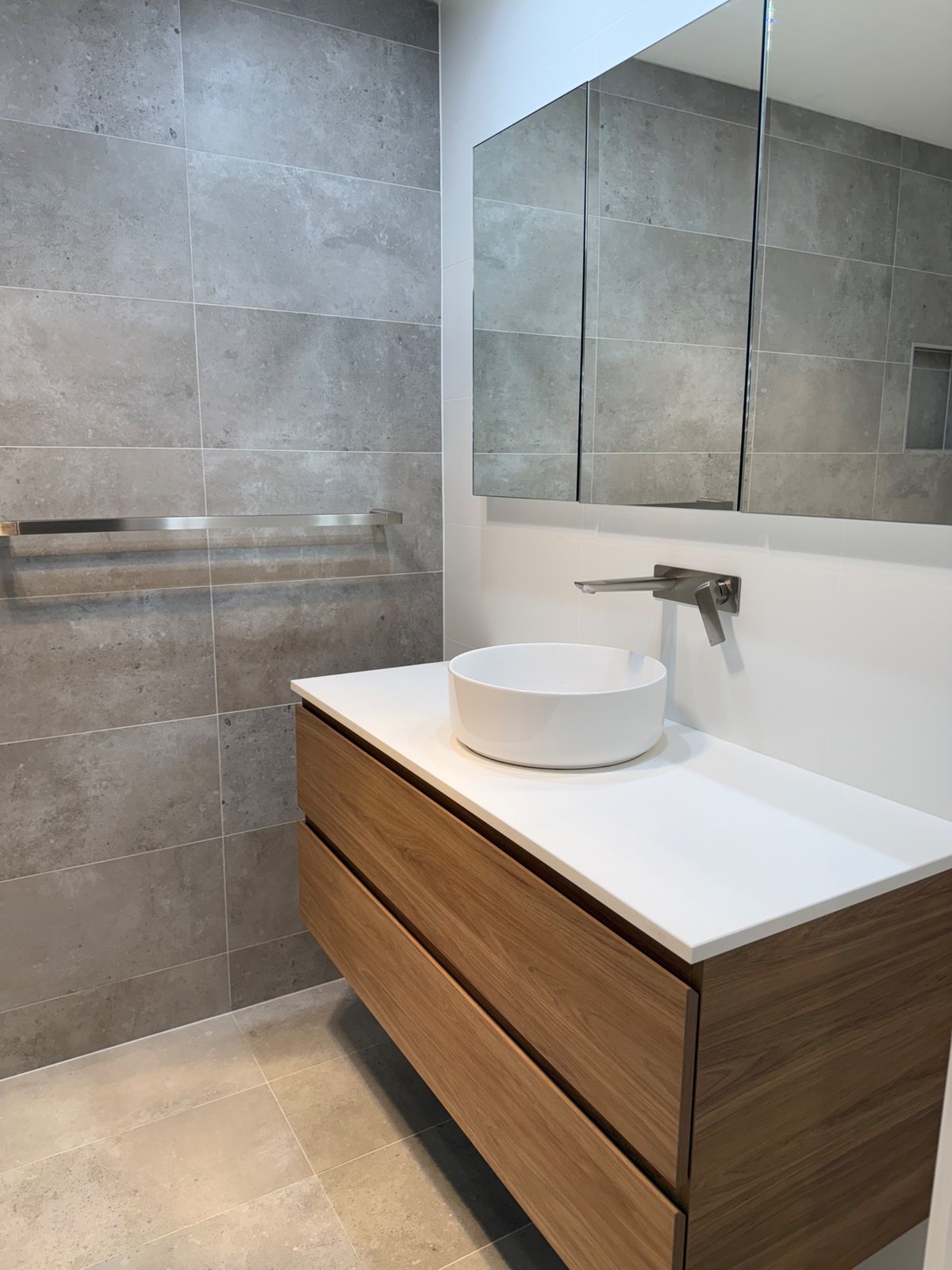 Renovated bathroom with a floating timber vanity, round vessel basin, wall-mounted brushed nickel tapware and large grey tiles