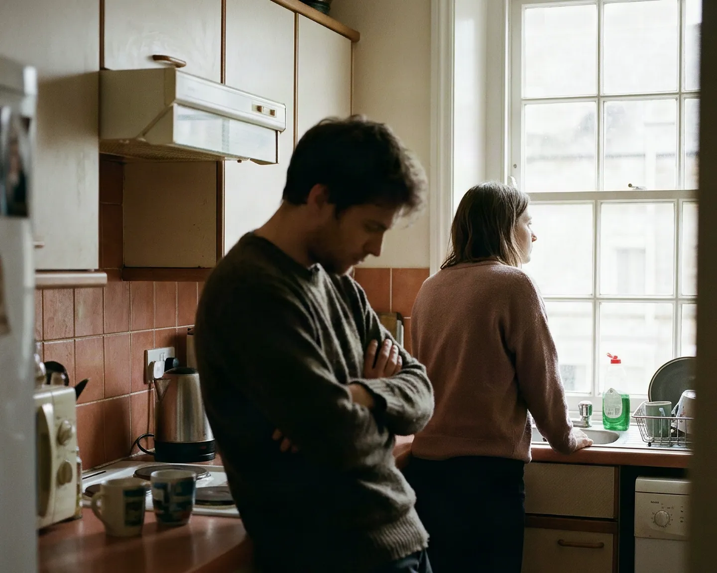 A couple standing apart in their kitchen after a disagreement