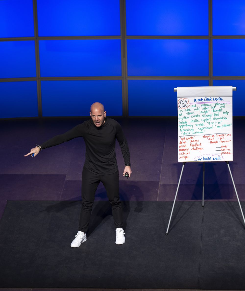 Ryan on stage pointing toward the audience beside a whiteboard