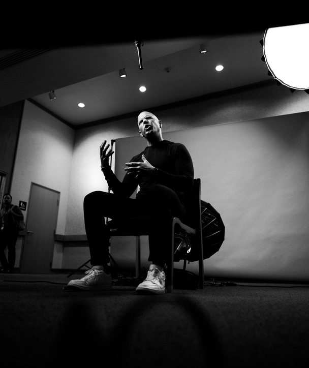 Ryan seated on a stage, mid-conversation, under studio lights