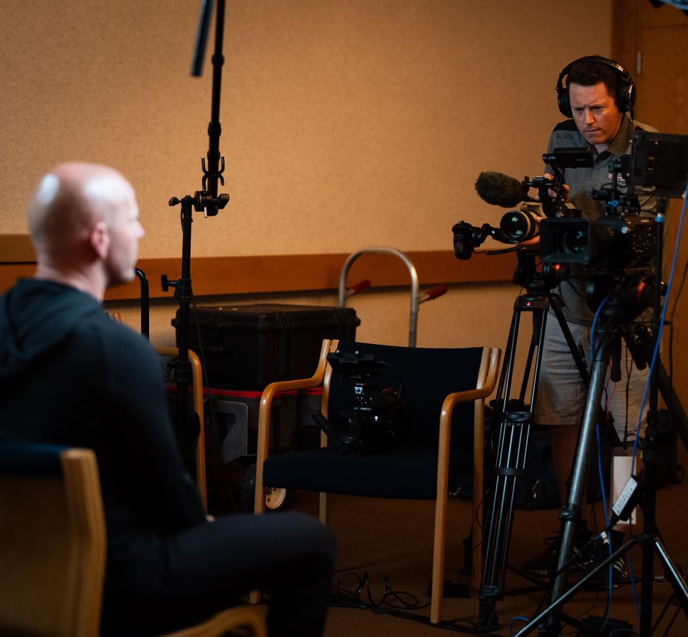 Ryan seated off to the side before an on-camera interview