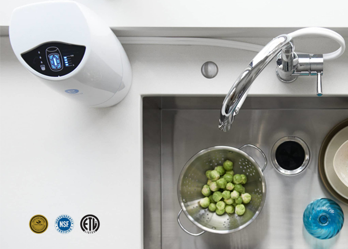 Overhead view of an eSpring water purifier with a digital display beside a kitchen sink and faucet