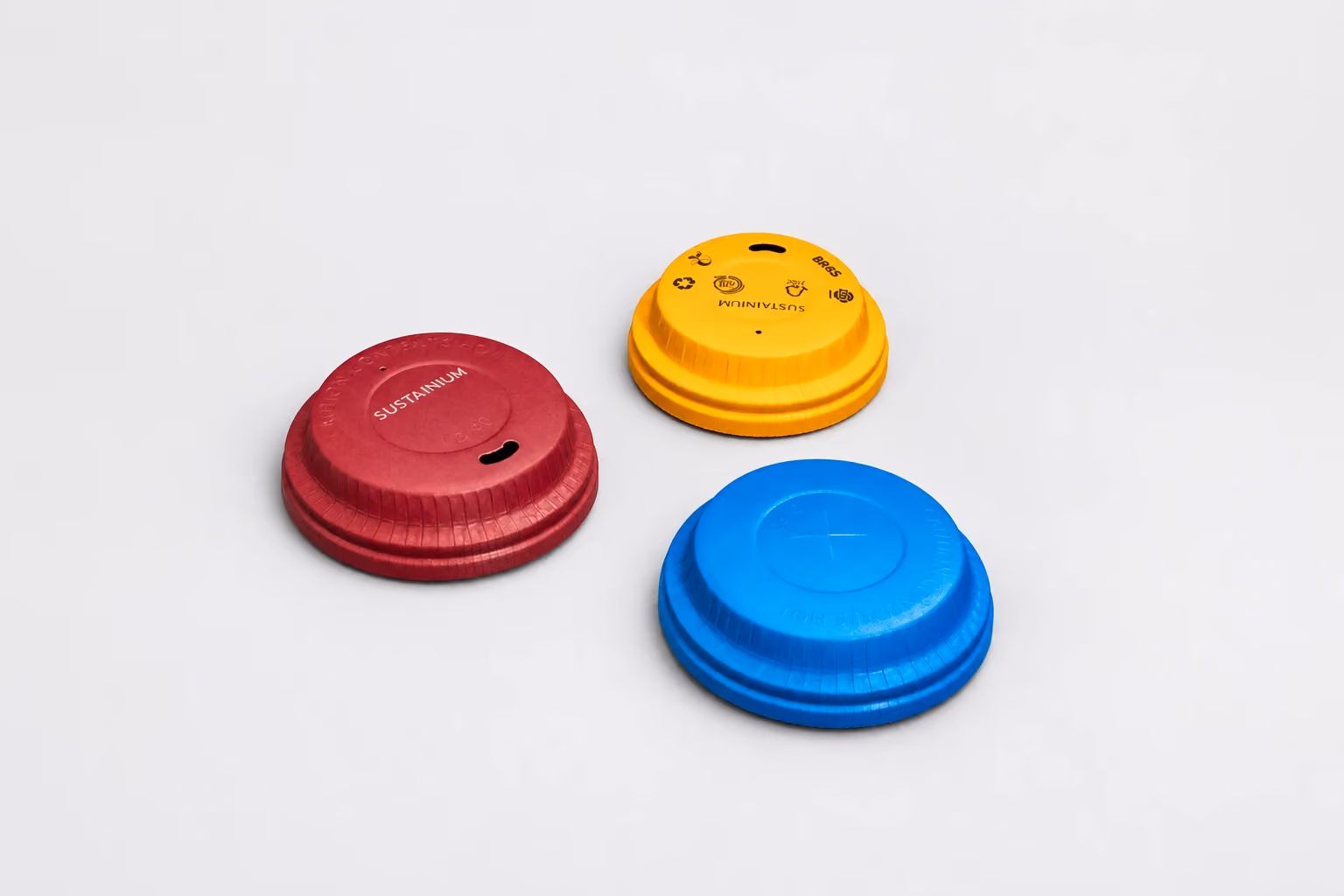 Burgundy, yellow and blue formed paper cup lids on light gray