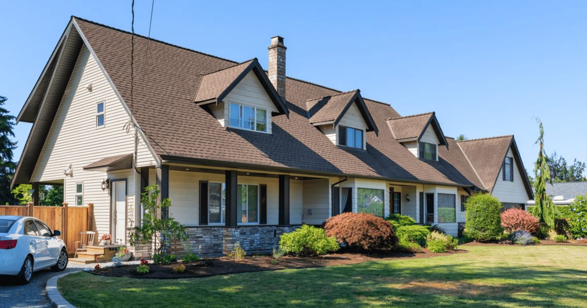 Two-storey custom home with dormer windows and a stone base, built by Koru Homes in Maple Ridge