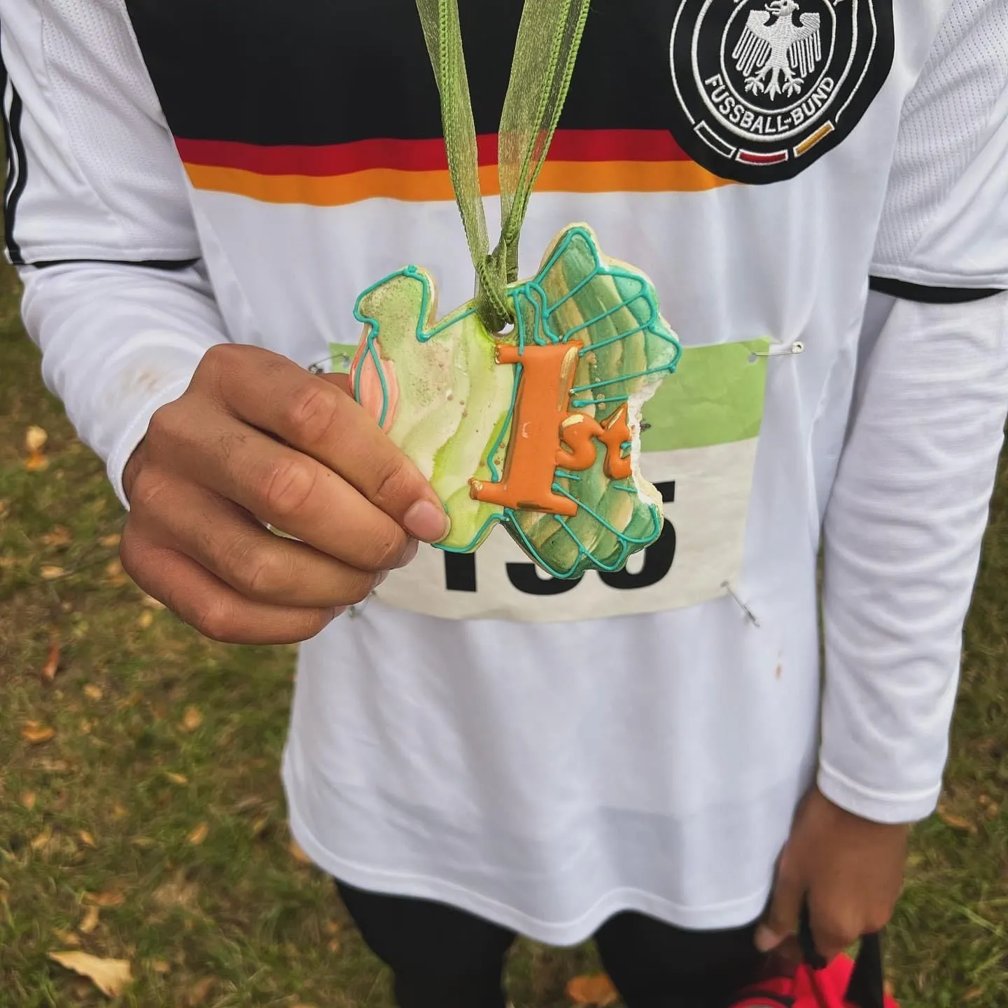 A runner holding up a cookie medal on a lanyard