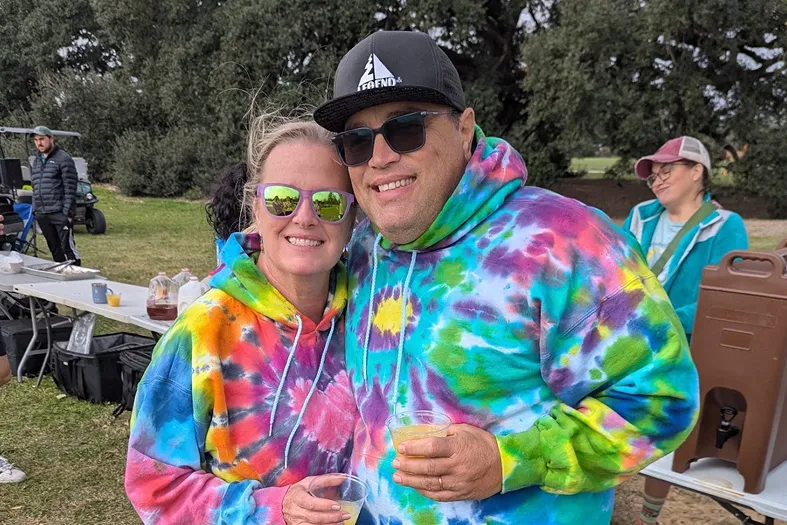 A smiling couple in matching tie-dye shirts at the Turkey Trot