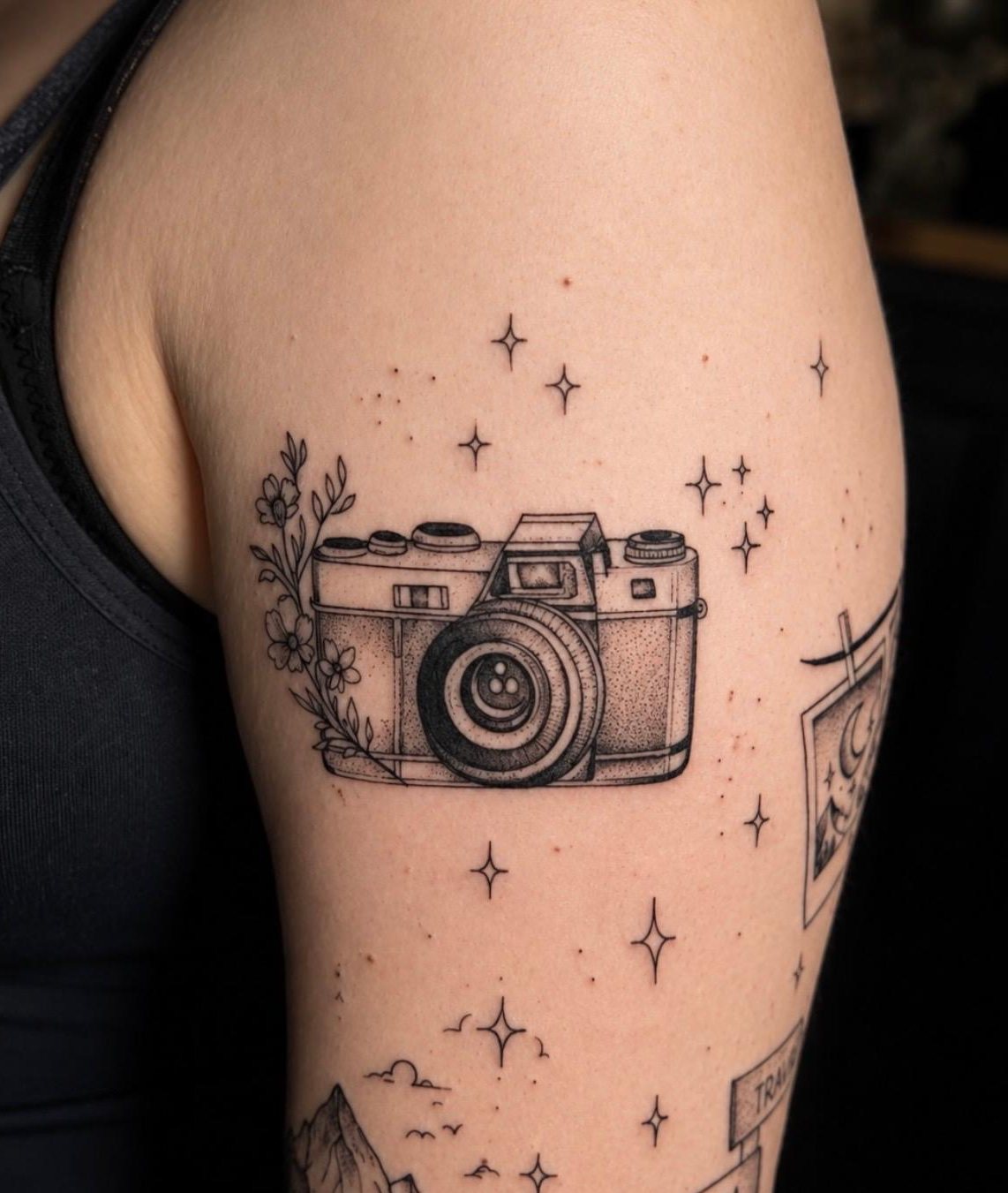 Fine line camera and stars tattoo on the upper arm by Asia at Squires Ink, Surfers Paradise