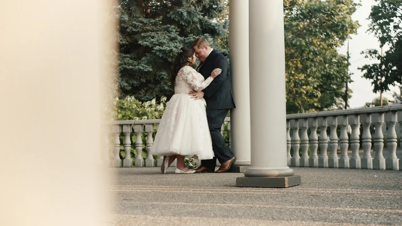 Breanna and Braden embracing beside a stone balustrade on their wedding day