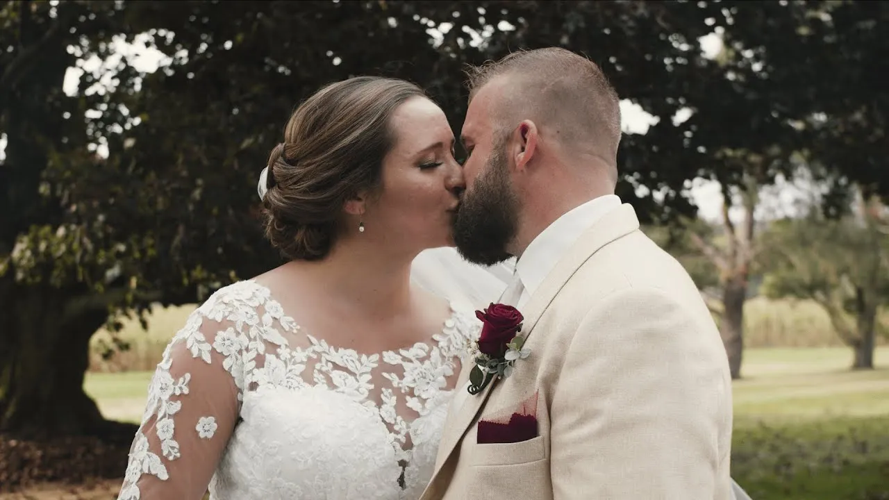 Connor and Jeff sharing a kiss beneath the trees on their wedding day
