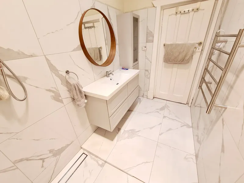Bathroom with large-format marble-look wall and floor tiles, a wall-hung vanity and a linear floor drain