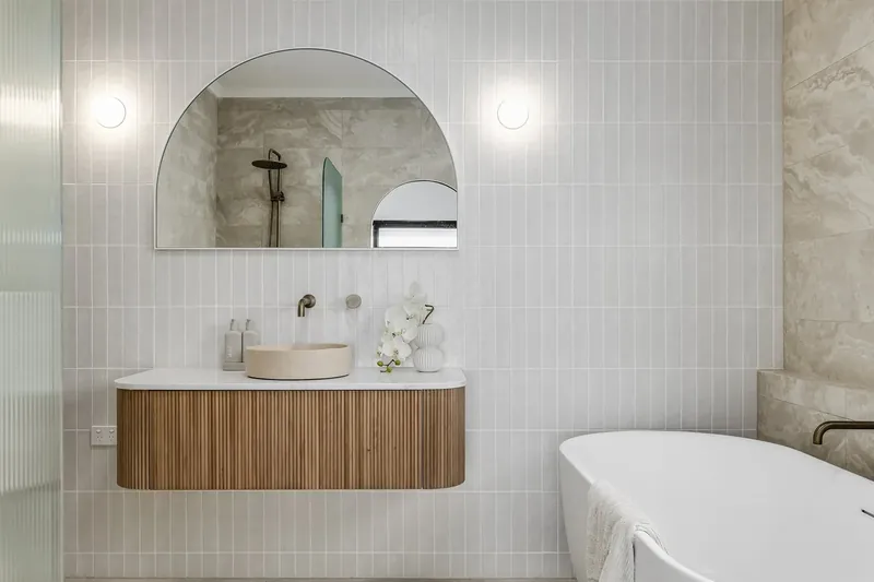 Wall and floor tiling in Bellevue Heights: a bathroom with a floating timber vanity under an arched mirror