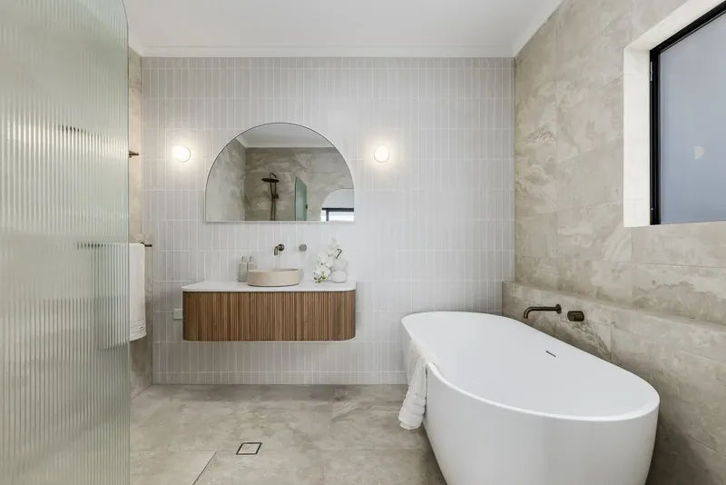 Bathroom floor and wall tiling in Bellevue Heights beside a freestanding bath