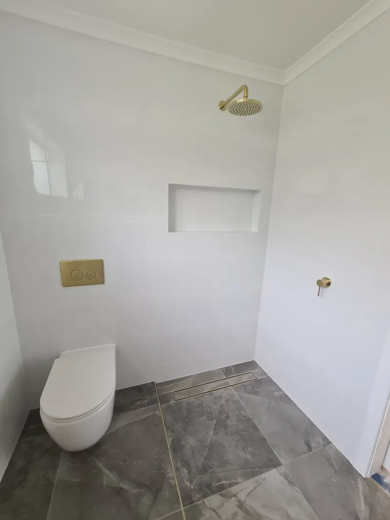 Bathroom wall and floor tiling: a bathroom with a wall niche, dark grey floor tiles and a wall-hung toilet