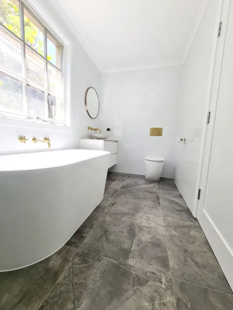 Bathroom wall and floor tiling, with a freestanding bath and dark grey floor tiles