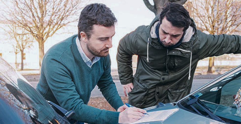 Deux bénévoles consultent une carte posée sur le capot d'une voiture