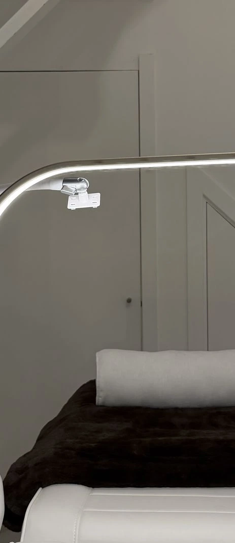 The Ffrench Lash treatment room: a white lash bed under a curved lash lamp, with the gold Ffrench Lash sign on the wall