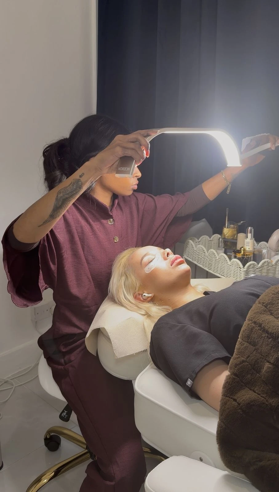 Jordy applying lash extensions to a client under the lash lamp in the Fulham studio