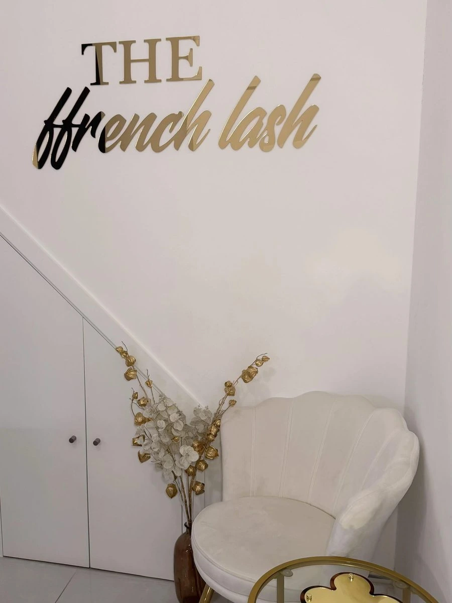 The gold Ffrench Lash sign above a cream shell chair in the private Fulham studio
