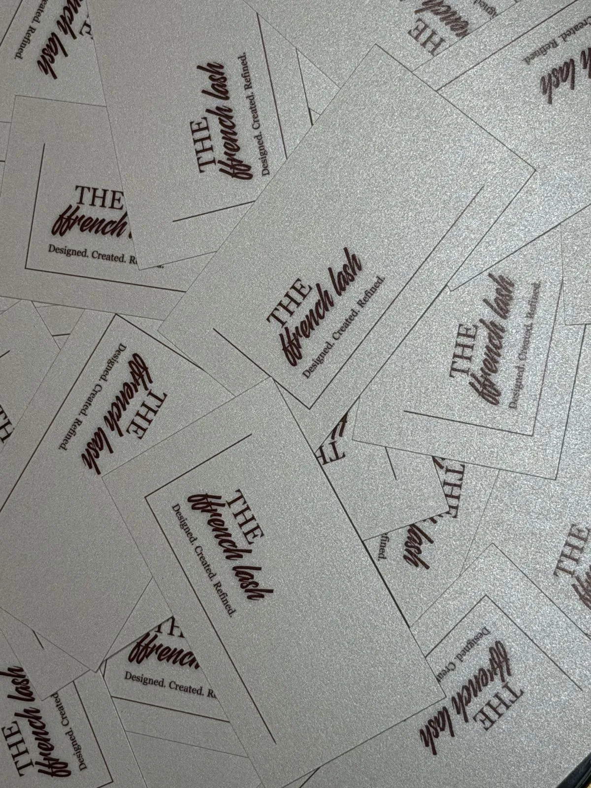A spread of Ffrench Lash business cards with the gold script logo