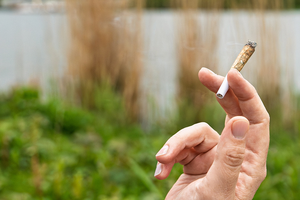 Hand holding a lit pre-roll outdoors