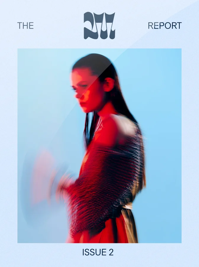 Blurred side profile of a woman with long dark hair wearing a red and black textured garment against a light blue background, featured on the cover of a magazine titled 'THE 207 REPORT ISSUE 2'.