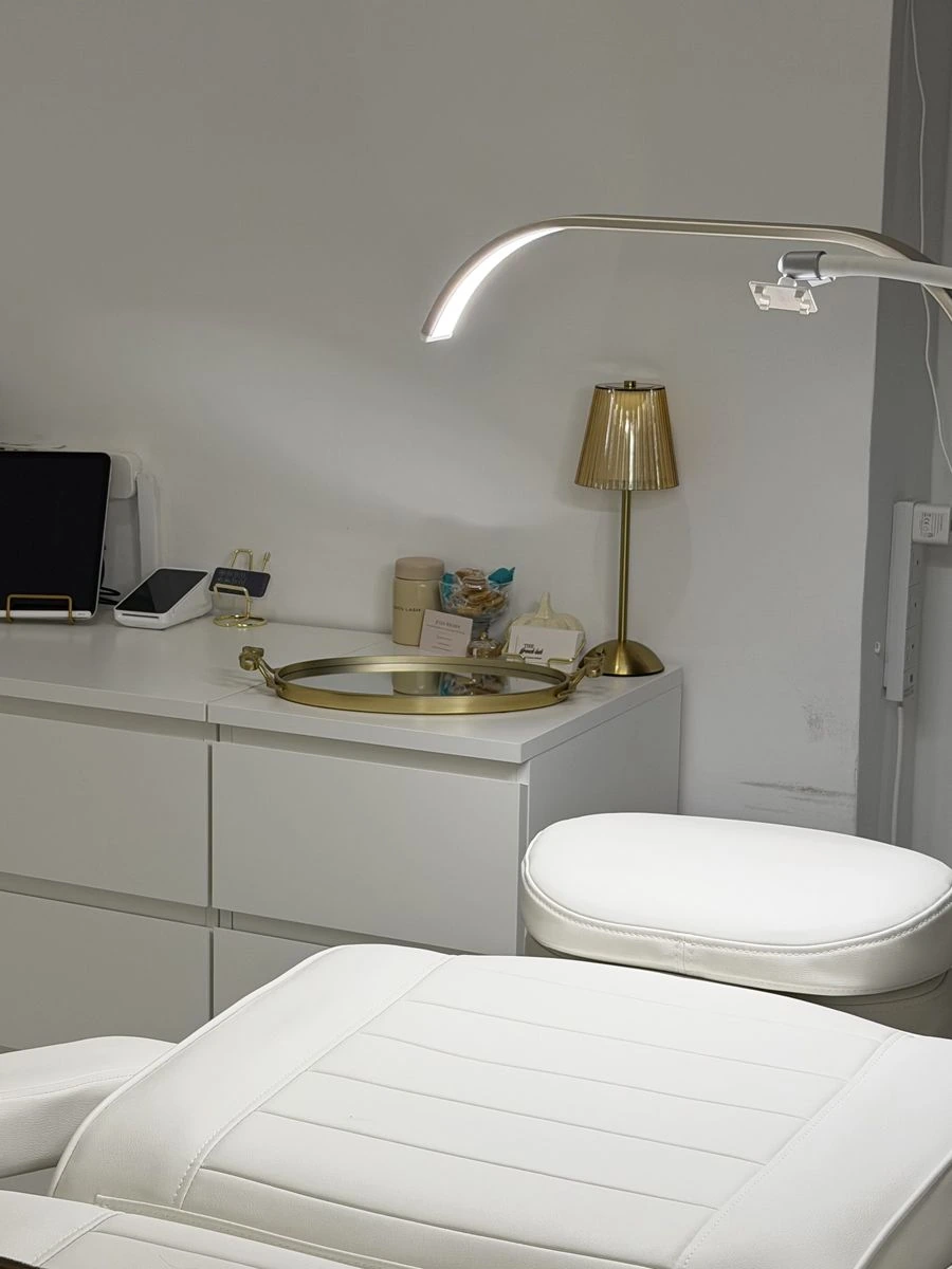 The treatment bed, gold lamp and lash lamp in the private Fulham studio, ready for a first visit