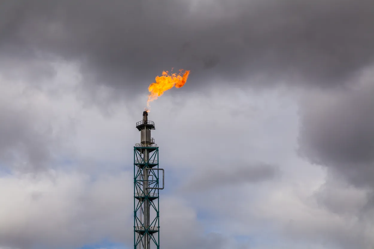 Flare stack burning under storm clouds