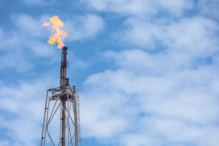 Flare stack burning against a blue sky