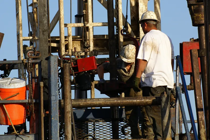 Roustabouts working on the lower platform of a drilling rig