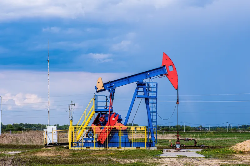 Blue and red pump jack in an open field