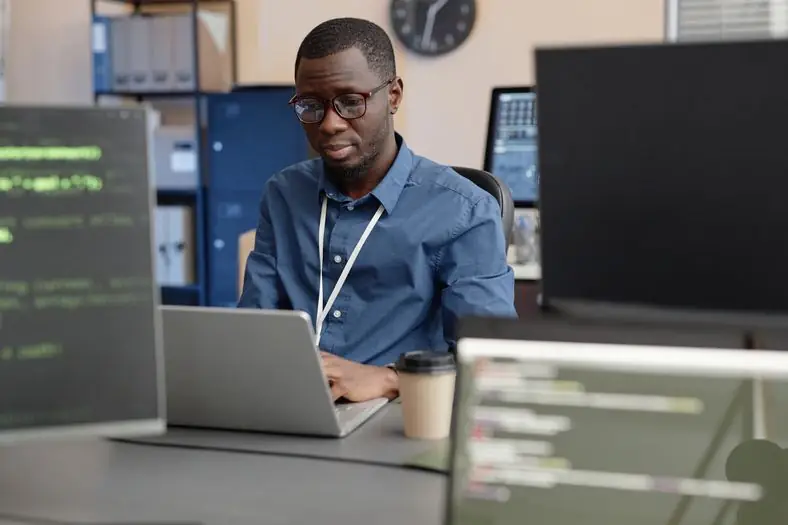 Engineer working on a laptop in a busy office