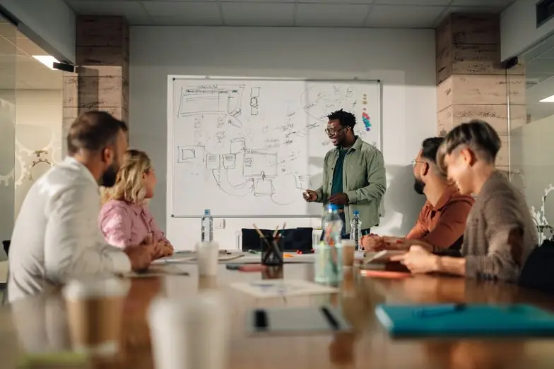 A consultant walks a client team through a plan on a whiteboard