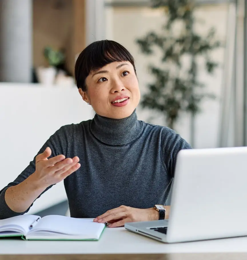A team member presents work on her laptop screen to colleagues