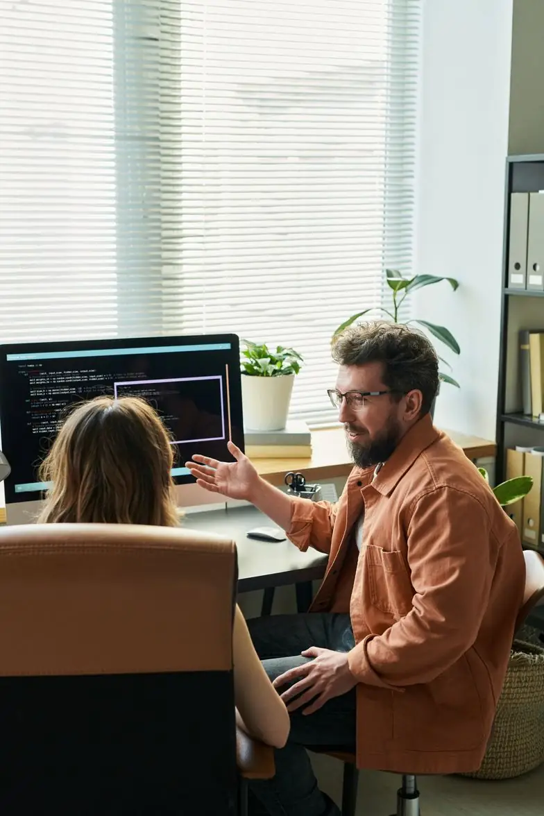 A team member explains something on his monitor to a colleague