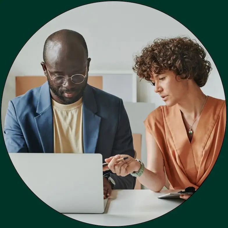 Two colleagues reviewing information together on a laptop