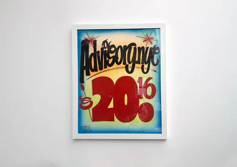Framed graffiti-style artwork reading Advisorynyc 2016 on a white wall