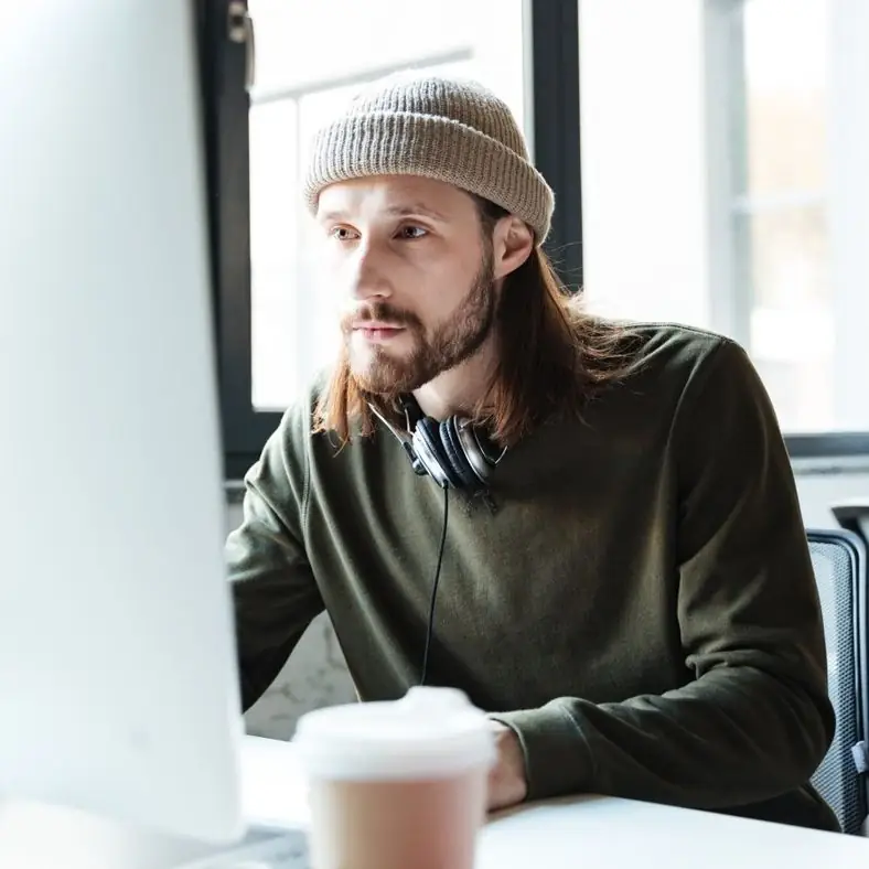 Engineer in a beanie and headphones working at a monitor