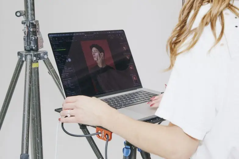 Hands working on a MacBook mounted on a stand in a photo studio